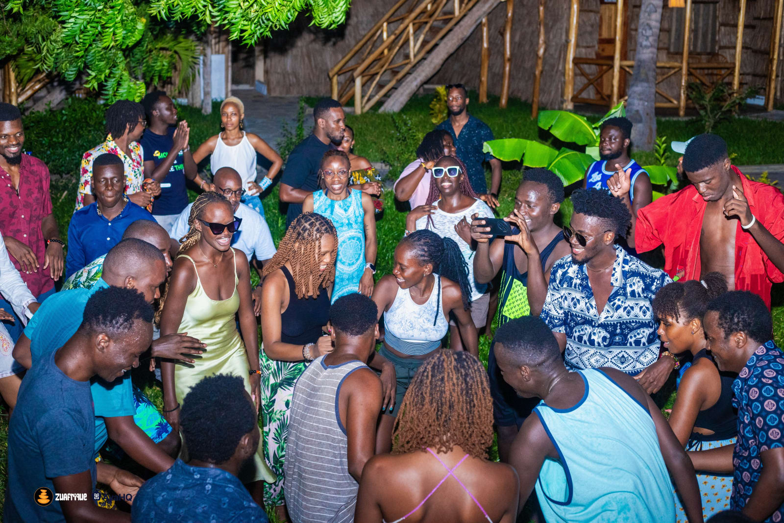 Residents dancing and cheering in a circle in a garden at night during the 2025 gathering.