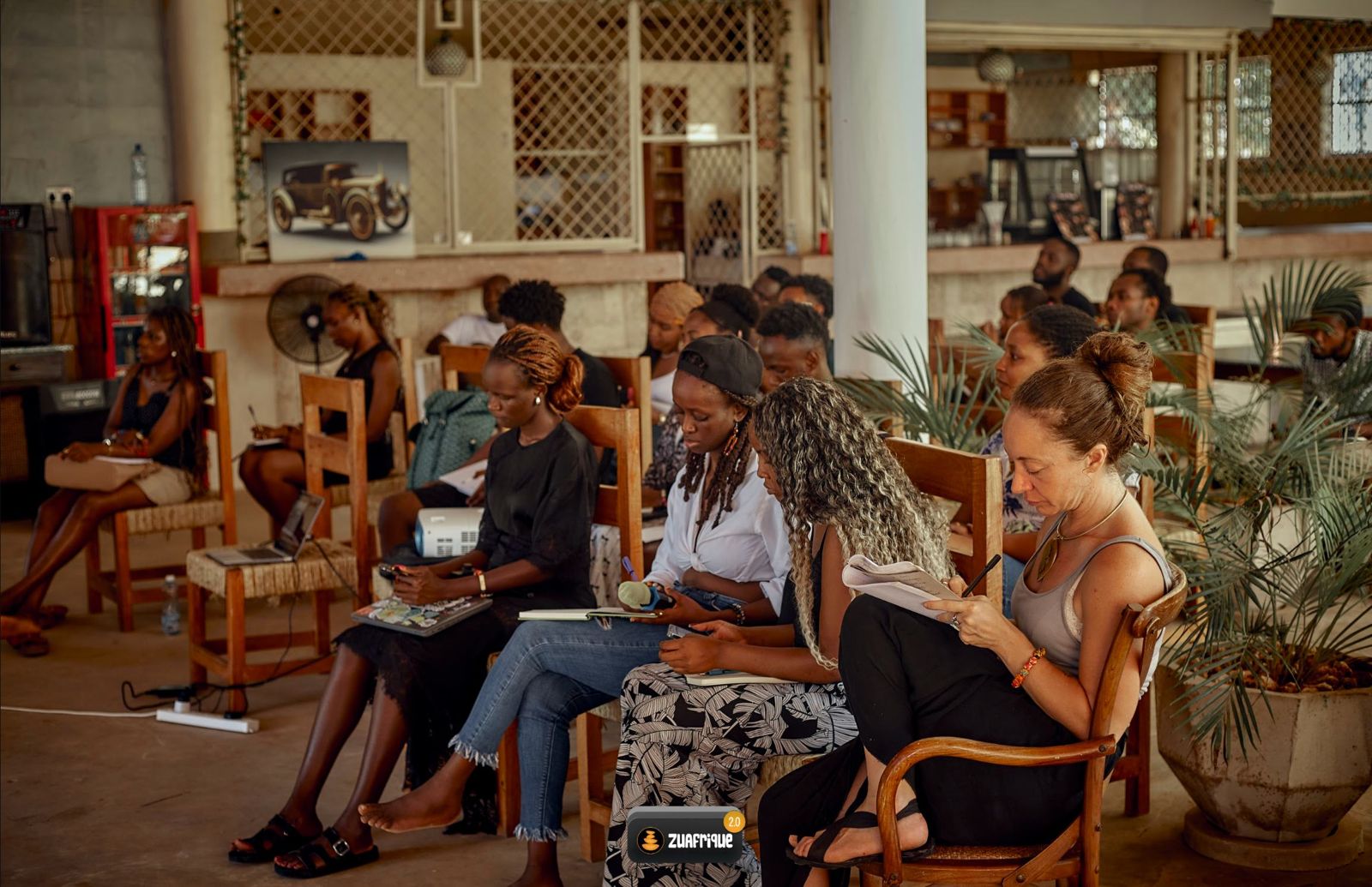 Residents seated in a bright open-air room, listening and taking notes during a session.